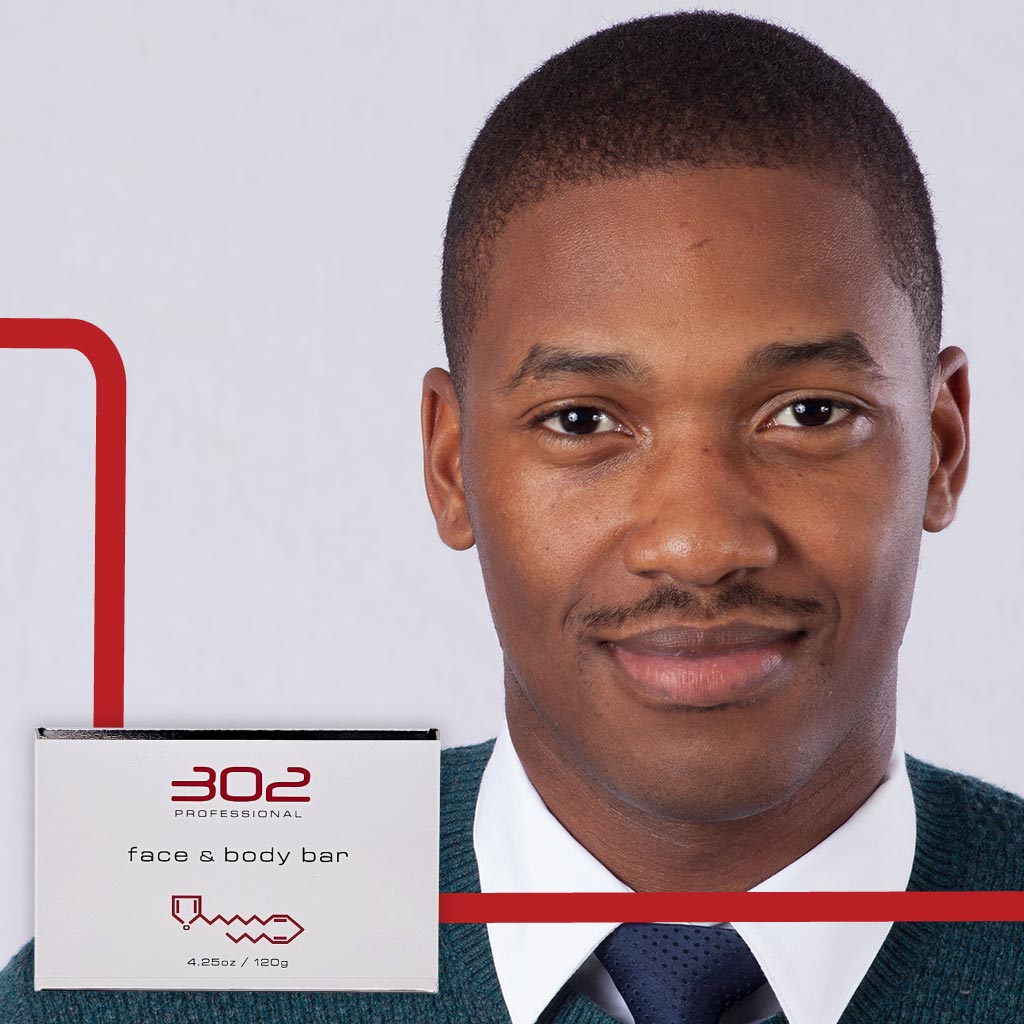 BAR-425OZ_MAN_1_1024x1024_72 | 302 Professional Skincare Man in suit smiles at the camera next to a product box labeled '302 Professional face & body bar' on a white background with red lines.
