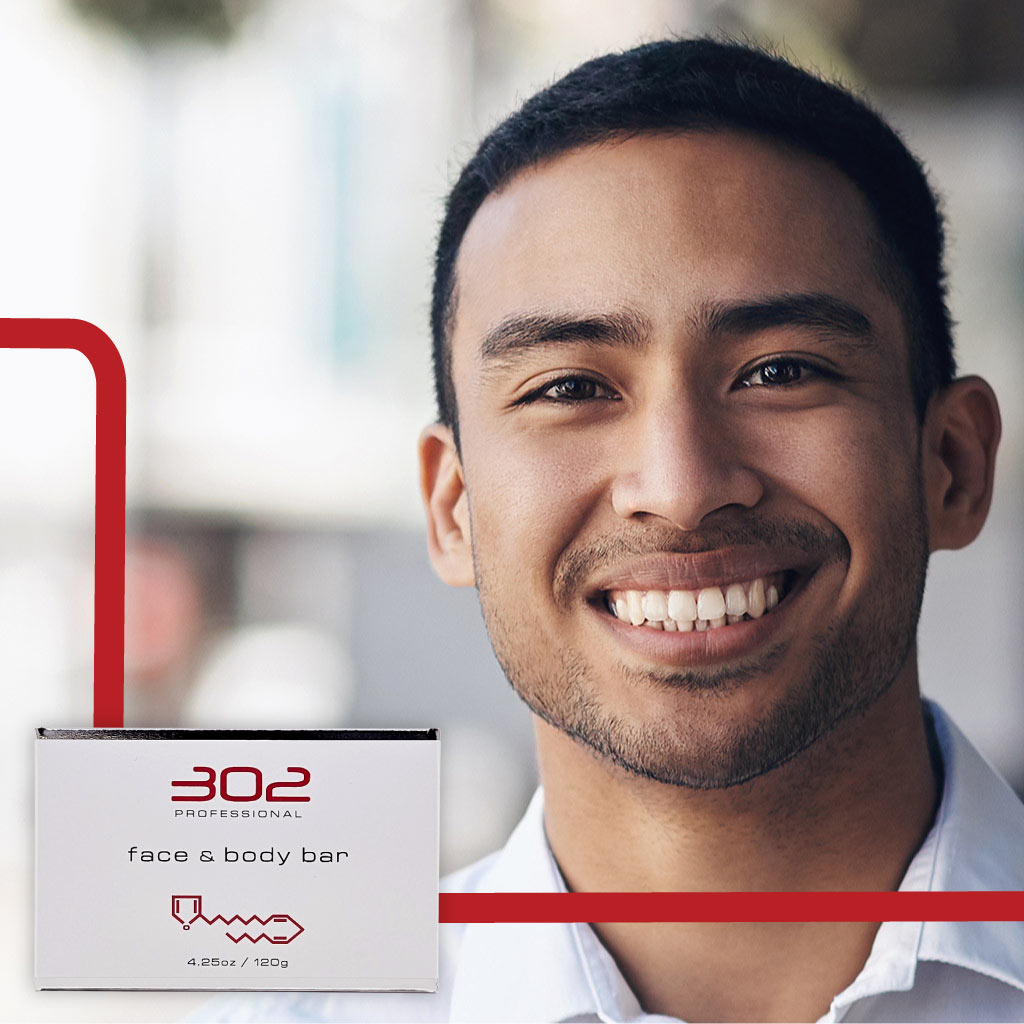 BAR-425OZ_MAN_2_1024x1024_72 | 302 Professional Skincare Smiling man next to a white box labeled 302 Professional face & body bar with red accents in the foreground.