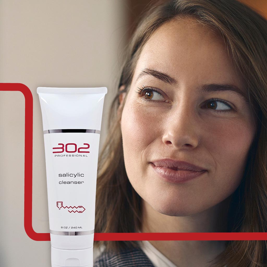 SALICYLIC-CLEANSER-8OZ_WOMAN_3_1024x1024_72 | 302 Professional Skincare Woman gazes to the side with a white tube of 302 Professional salicylic cleanser in the foreground.